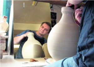 Der Töpfer Ingo Müller dreht in seiner Werkstatt in Haina eine große bauchige Vase. Im Spiegel kann er das Werkstück einfacher überprüfen. Foto: C. Hoppe 